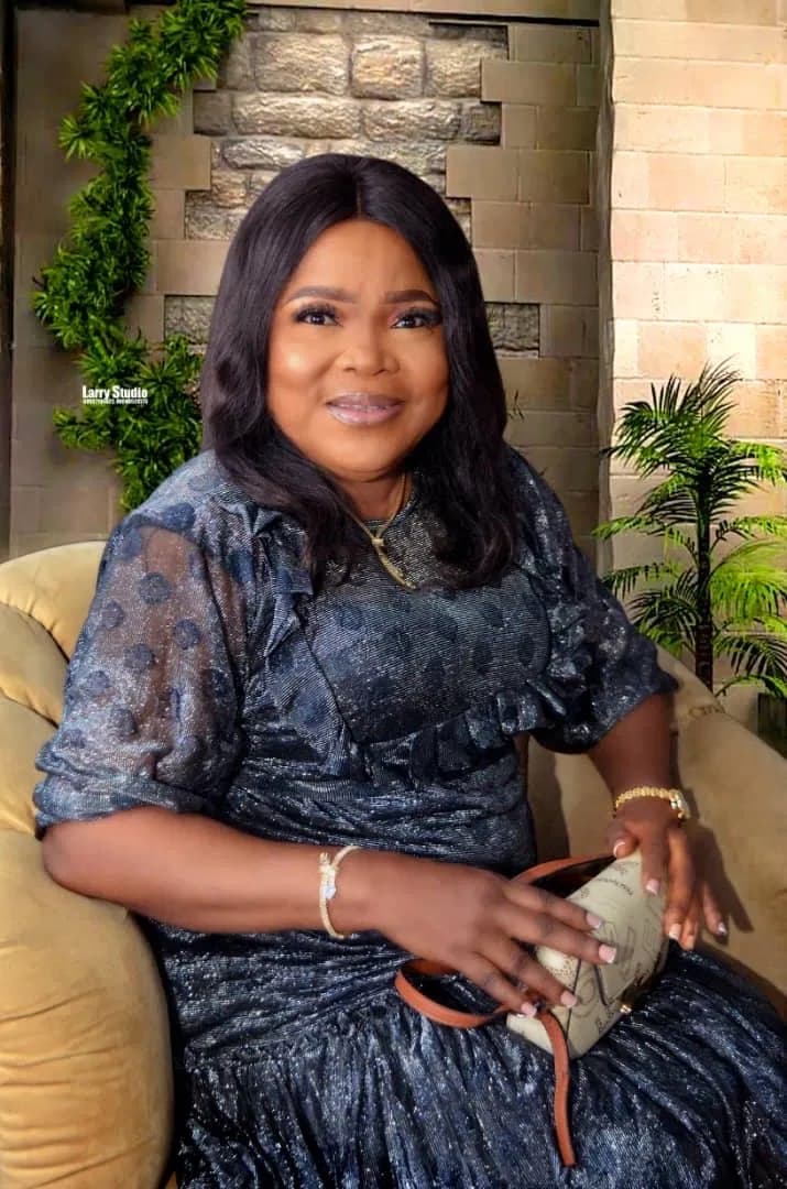 Yeside Ilesanmi, seated, smiling, in a navy and silver dress