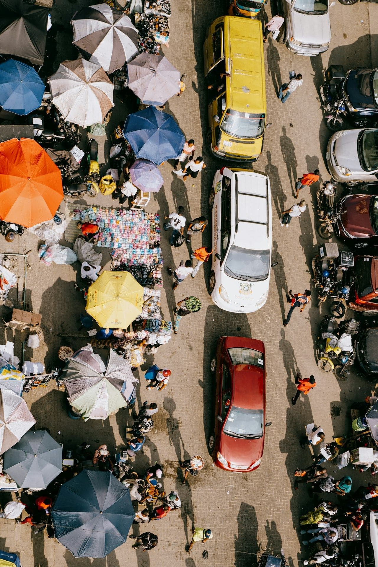 Market stalls, umbrellas and traffic seen from above