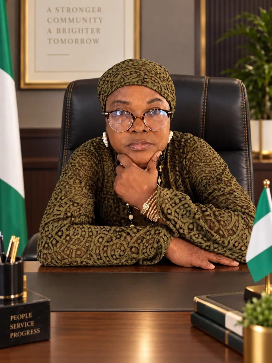 Yeside Ilesanmi at her desk in olive lace, chin resting on her hand